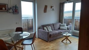a living room with a couch and a glass table at Mezonetový apartmán se dvéma balkóny a výhledem in Loučná pod Klínovcem