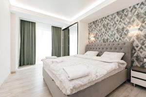 a bedroom with a large bed with a gray headboard at Luxury Apartment in Chişinău