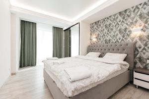 キシナウにあるLuxury Apartmentのベッドルーム1室(大型ベッド1台、グレーのヘッドボード付)