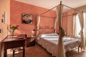 1 dormitorio con cama con dosel, mesa y escritorio en B&B Villa Barbarossa, en Petrignano