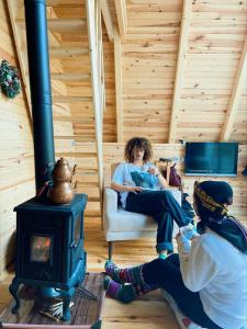 two women sitting in a room with a stove at Lelvani Suite Bungalow in Rize