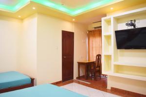 Habitación con cama, TV y mesa. en Hostal Galápagos - Guayaquil, en Guayaquil