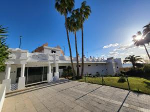 une maison blanche avec des palmiers devant elle dans l'établissement Apartamento SOLSILK, à Torremolinos