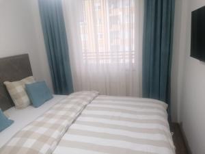 a bed in a bedroom with blue curtains and a window at Sofija City BL in Banja Luka