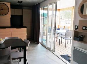 a kitchen and dining room with a table and a balcony at Cottage chaleureux Louann in Labouheyre