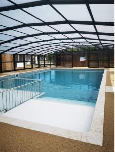 a large swimming pool with blue water in a building at Cottage chaleureux Louann in Labouheyre