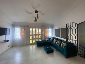 un salon avec un canapé bleu et une télévision dans l'établissement La Villeneuvoise, à Mbour