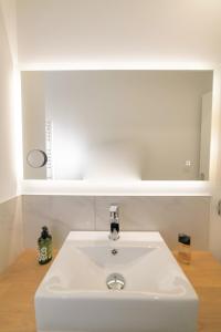 La salle de bains est pourvue d'un lavabo blanc et d'un miroir. dans l'établissement Le Graff - Locationtournus, à Tournus
