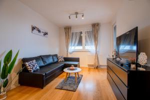a living room with a black leather couch and a tv at Flexible SelfCheckIns 41 - Zagreb - Luxury - Parking - Loggia - Brand New in Zagreb