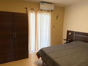 1 dormitorio con cama y ventana en DEPARTAMENTO DON GENARO en Villa Carlos Paz