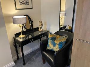 1 dormitorio con silla y escritorio con lámpara en THE OCEAN SUITE - 2 minute walk to the lovely beach front promernade of llandudno en Llandudno