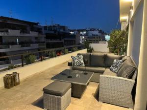 a patio with a couch and a table on a balcony at Athens Neos Kosmos penthouse, sea and city view in Athens