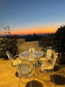 a patio table and chairs with a sunset in the background at Athens Neos Kosmos penthouse, sea and city view in Athens