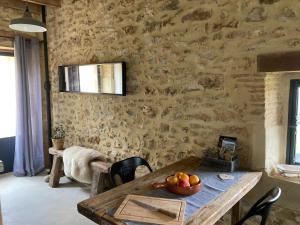 een eetkamer met een tafel en een stenen muur bij Maison Secrete Apartment 1 in Marsalès