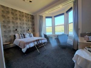 una camera con letto, sedia e finestre di Lawriestone Guest House a Fort William