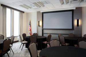 una sala de conferencias con mesas, sillas y una pantalla en Hyatt Place New Orleans Convention Center, en Nueva Orleans