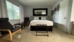 ein Schlafzimmer mit einem Bett, einem Stuhl und einem Stuhl in der Unterkunft White Horse Motel in Lake Worth