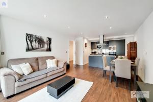 uma sala de estar e cozinha com um sofá e uma mesa em Fully Serviced Two Bed Apartment by ExCeL & O2 em Londres