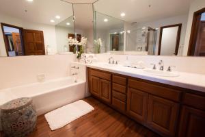 ein Badezimmer mit zwei Waschbecken, einer Badewanne und einem großen Spiegel in der Unterkunft Premium Ocean Corner Unit, Fireplace, Golf Cart, 21 Steps from Top in Avalon