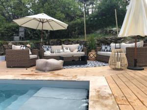 a patio with couches and an umbrella and a pool at Mas du Tracol - Roulotte in Les Assions