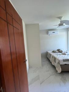 1 dormitorio con 1 cama y puerta de madera en CasaCactus em Tamoios na quadra da praia junto a Barra de São João, en Cabo Frío