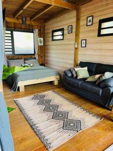 a living room with a couch and a bed at Ô Palm : dans un petit écrin de verdure in Saint-Joseph