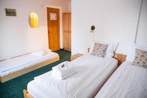 a room with two beds with white sheets at Casa Bogát Ház in Harghita-Băi