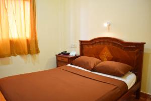 Bett mit einem Kopfteil aus Holz in einem Schlafzimmer in der Unterkunft Hostal Galápagos - Guayaquil in Guayaquil