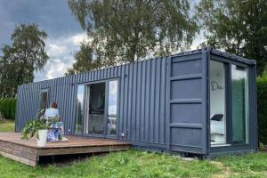 a small grey shipping container with a woman sitting on a deck at Le Grand Biseu in Stavelot +6 photos