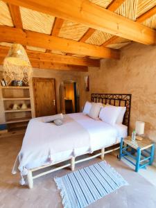 ein Schlafzimmer mit einem Bett und einer Holzdecke in der Unterkunft Maison d'hôtes Tigminou - Adults Only in Aït-Ben-Haddou