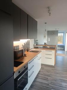a kitchen with white cabinets and a wooden floor at Le Grand Biseu in Stavelot