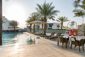 3 Bedroom townhouse furnished في دبي: مسبح وكراسي وطاولة بجانب مسبح