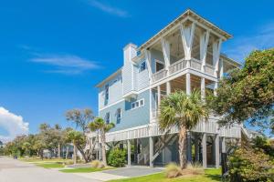 a large white house with palm trees in front of it at Naut A Bad Gig in Oak Island