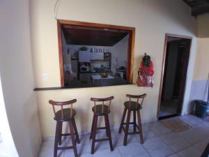 a room with three bar stools and a mirror at Maravilhosa praia do Sargi - BA in Serra Grande