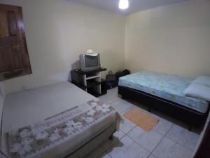 a small bedroom with two beds and a tv at Maravilhosa praia do Sargi - BA in Serra Grande