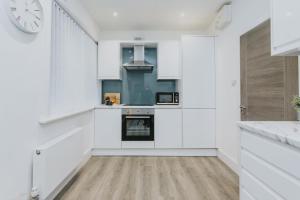a kitchen with white cabinets and a clock on the wall at Spacious Apartment Near City Centre - Free Parking, Wi-Fi with King Size Bed in Nottingham