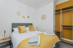 um quarto com uma grande cama branca com almofadas amarelas em Spacious Apartment Near City Centre - Free Parking, Wi-Fi with King Size Bed em Nottingham