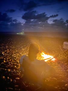a person sitting on a beach with a fire at La Luna Elyu 