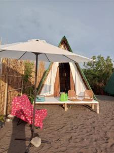 a tent with two chairs and an umbrella at La Luna Elyu 