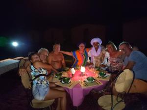 un grupo de personas sentadas alrededor de una mesa en Bivouac Le charme d'Aladdin, en El Gouera