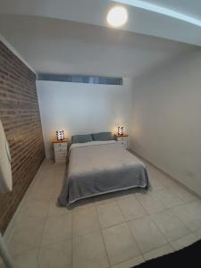 a bedroom with a bed and a brick wall at Alquiler por día General Villegas in General Villegas