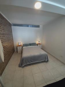 a bedroom with a bed and a brick wall at Alquiler por día General Viilegas in General Villegas