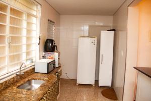 cocina con fregadero y nevera blanca en Apartamento Gutierrez 1, en Belo Horizonte