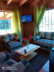 ein Wohnzimmer mit Sofas und einem Tisch mit Blumen darauf in der Unterkunft Cabañas Aitue Kasablanka Cudico en LicanRay in Licán Ray
