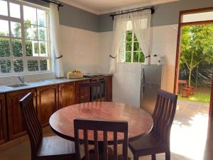 La cuisine est équipée d'une table, de chaises et d'un réfrigérateur. dans l'établissement Daria Apartment -Burka -3 minutes from Arusha Airport, à Arusha