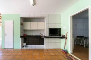 cocina con paredes de azulejos blancos y puerta abierta en Casa com 4 Dormitórios a 130 metros da praia de Bombas, en Bombinhas