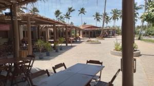 een patio met tafels en stoelen en palmbomen bij Casa em Imbassai in Imbassai