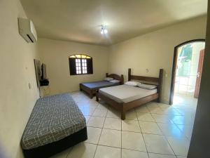 1 dormitorio con 2 camas y ventana en Boca da Lagoa - Onde o Sol, o Mar e a Montanha se Encontram, en Boicucanga