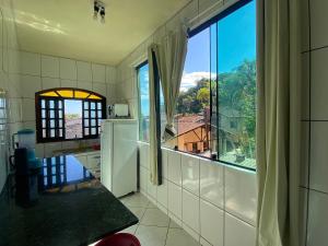une cuisine avec une grande fenêtre offrant une vue dans l'établissement Boca da Lagoa - Onde o Sol, o Mar e a Montanha se Encontram, à Boicucanga