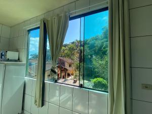 a bathroom window with a view of a mountain at Boca da Lagoa - Onde o Sol, o Mar e a Montanha se Encontram in Boicucanga